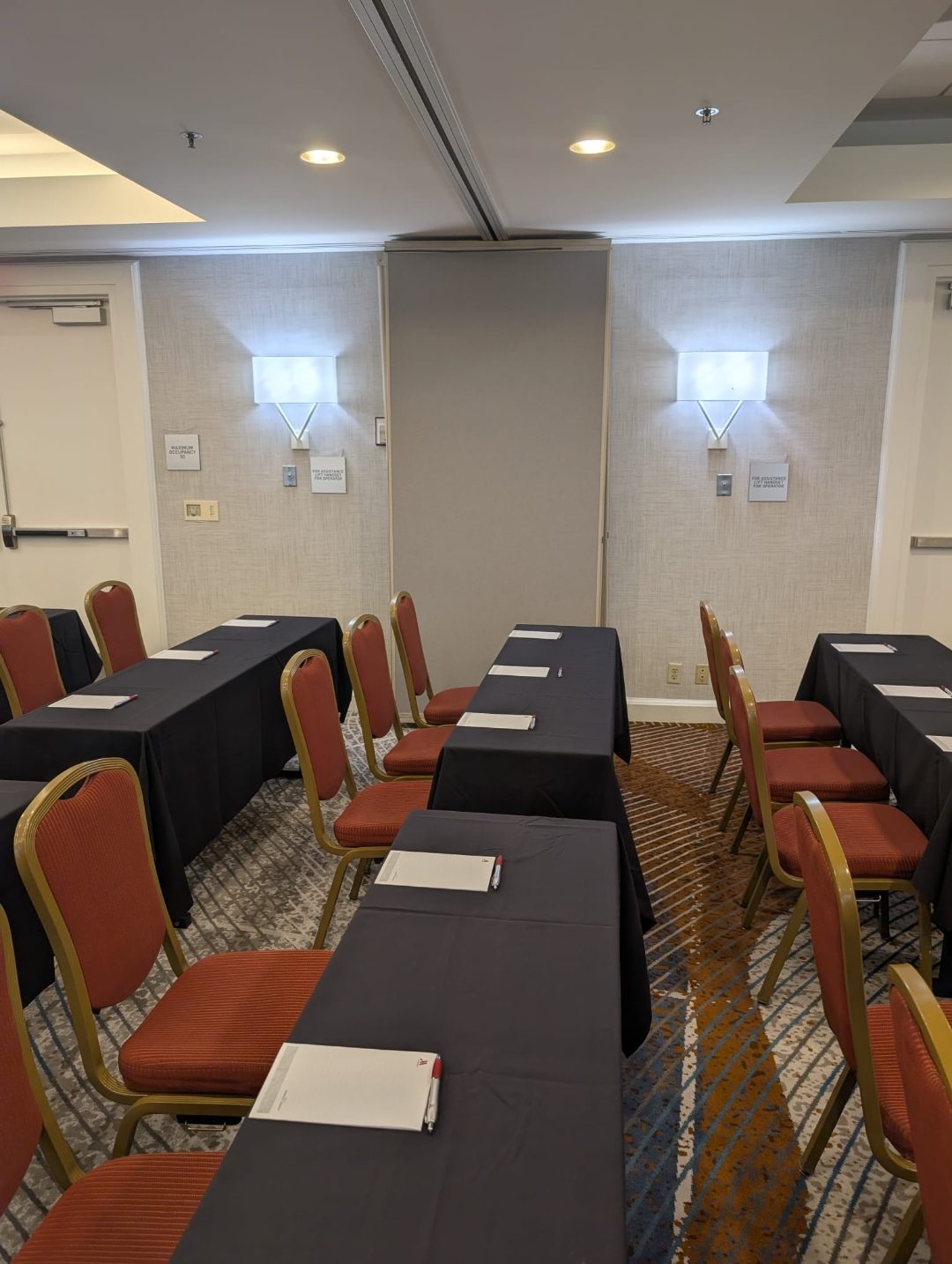 Corporate meeting room set classroom-style with black-linen tables and notepads