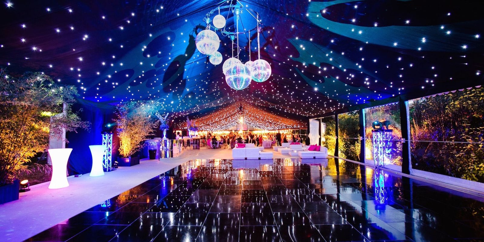 Tented reception with starry-night ceiling, string lights, and a mirrored dance floor