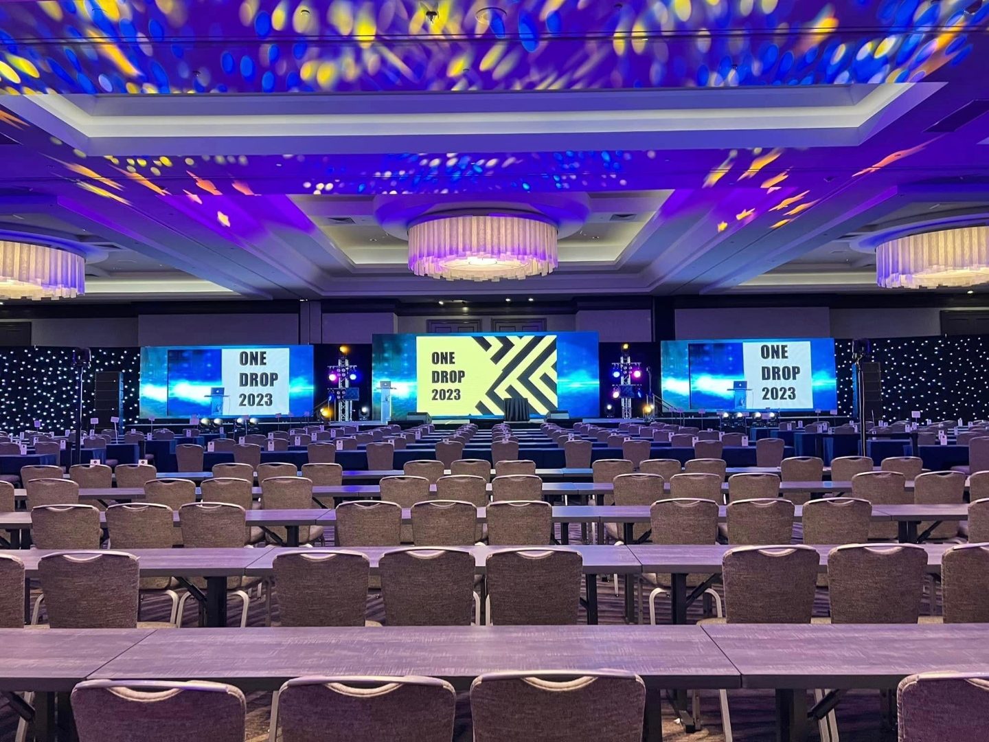 Corporate summit ballroom set with a triple-screen main stage